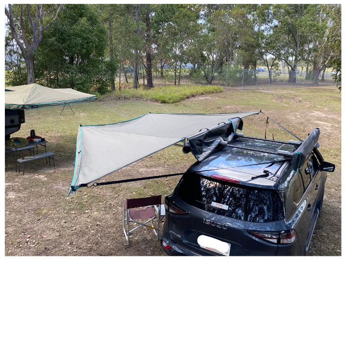 A gray 30 Second Wing Awning attached to a vehicle, providing shade over an outdoor table and chairs.